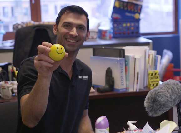 TSC Team Member holding up a small yellow smiley face ball